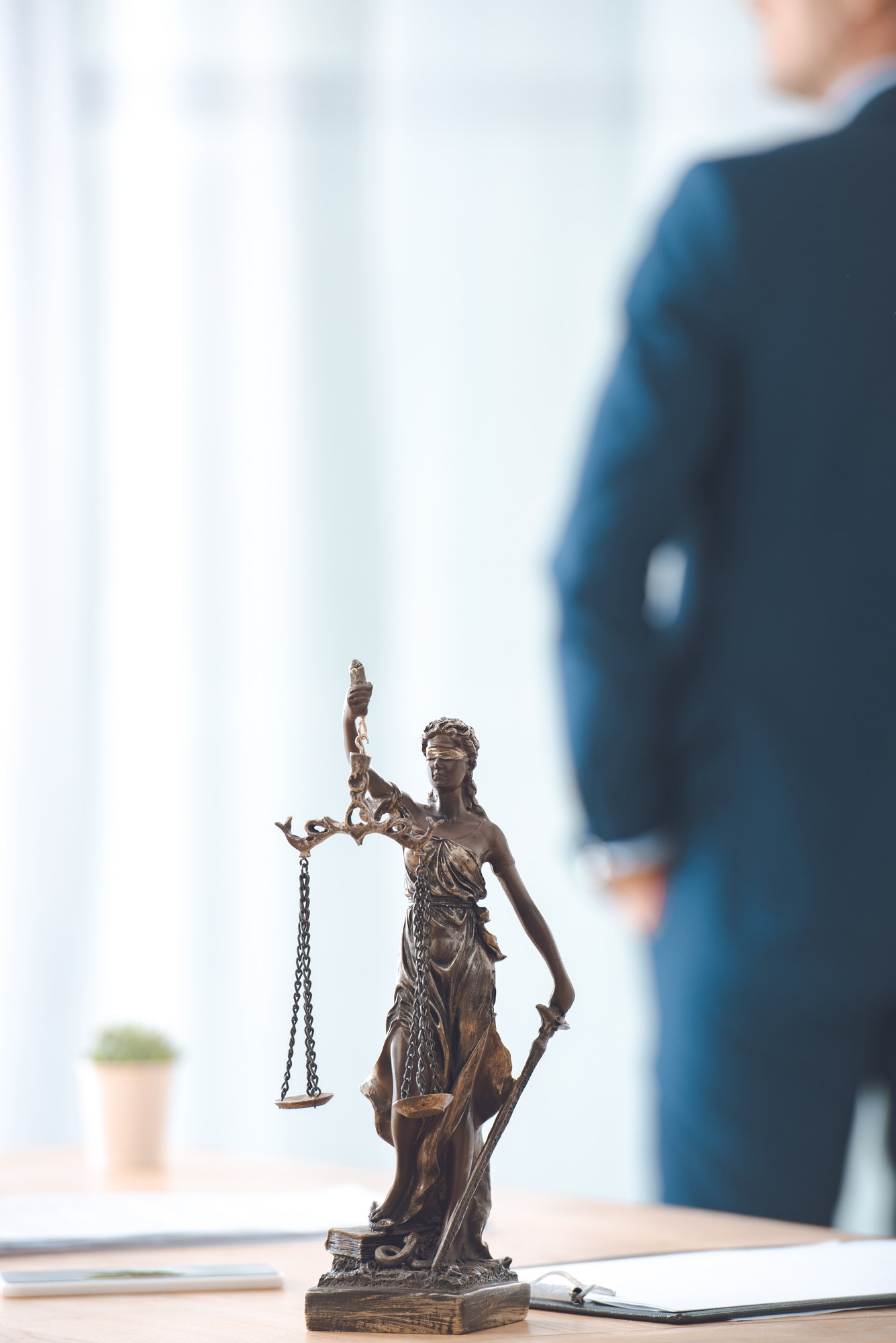 close-up view of lady justice statue and lawyer standing behind